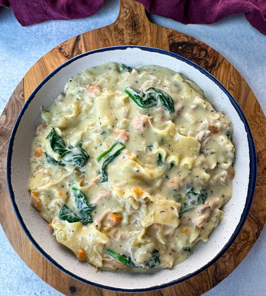 white lasagna soup in a bowl with carrots, celery, and spinach