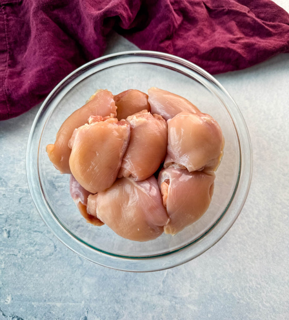 raw boneless, skinless chicken thighs in a glass bowl