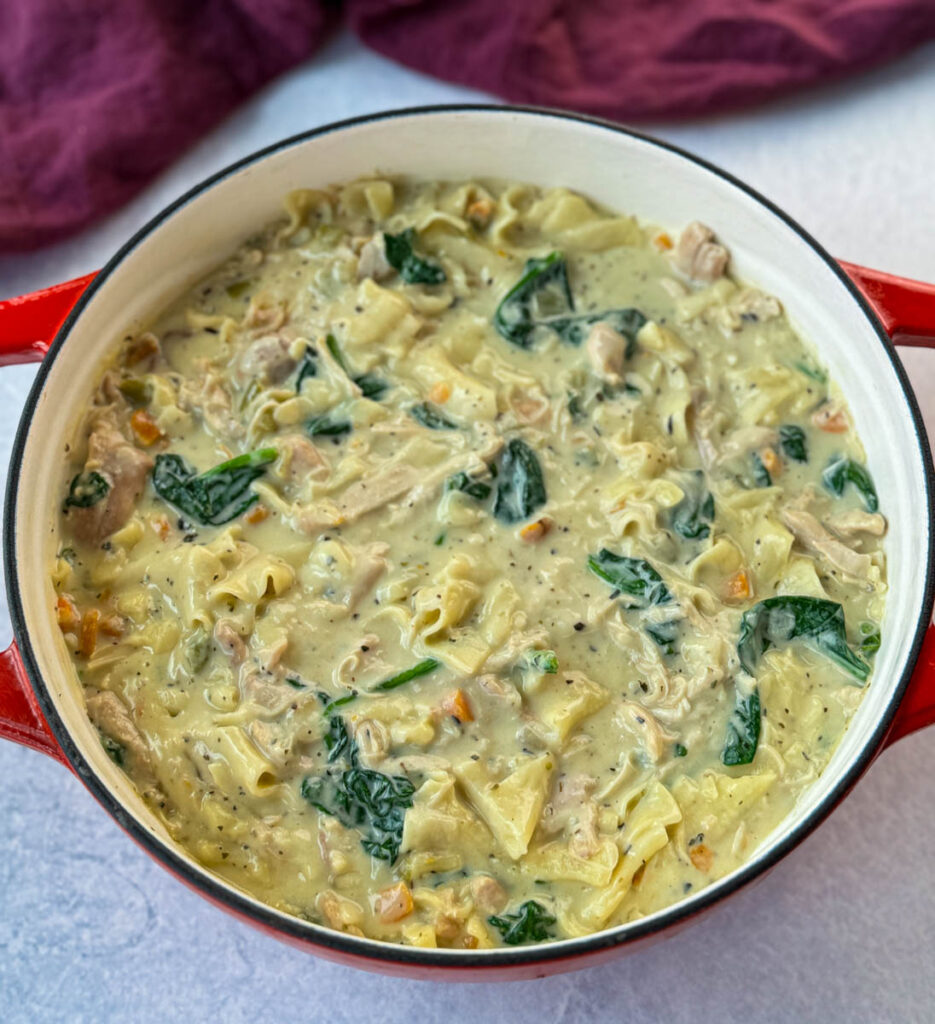 white lasagna soup in a Dutch oven with carrots, celery, and spinach