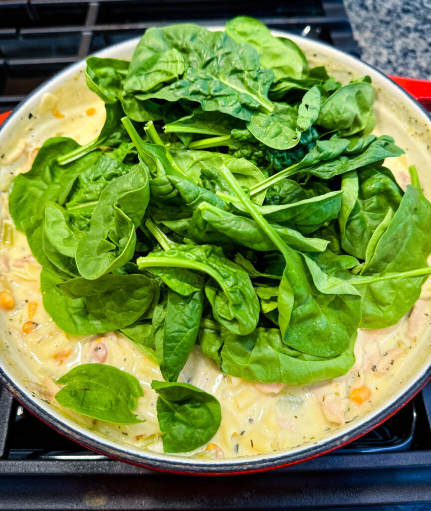 white lasagna soup in a Dutch oven with spinach