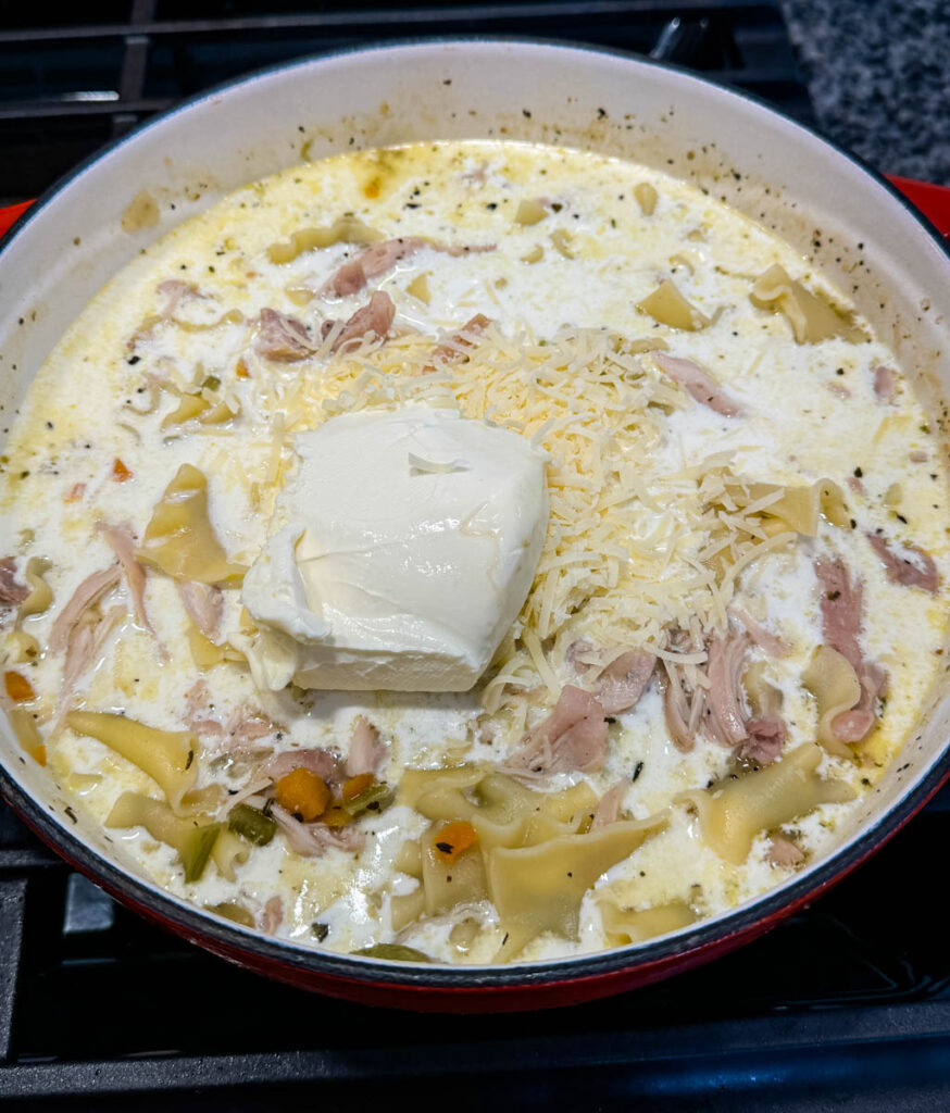 white lasagna soup in a Dutch oven with cream cheese