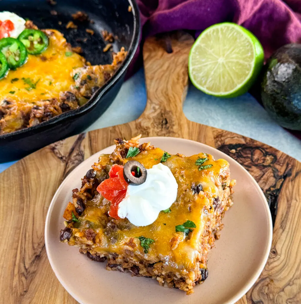 Mexican beef and rice taco skillet dish on a plate with sour cream, tomatoes, and black olives