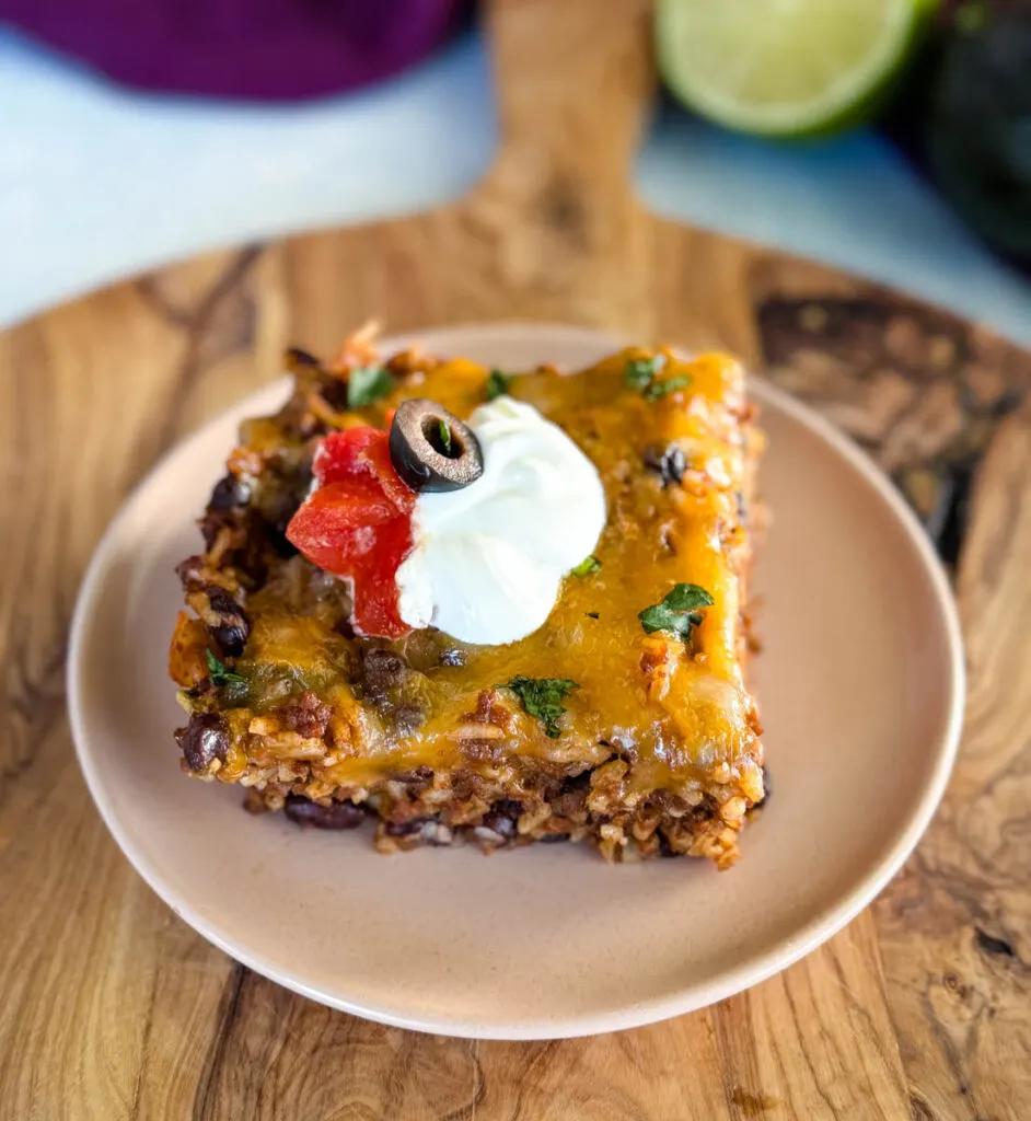 Mexican beef and rice taco skillet dish on a plate with sour cream, tomatoes, and black olives