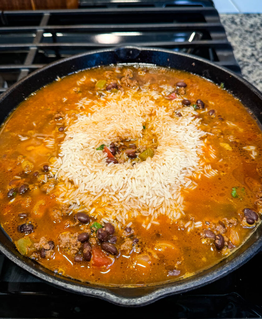 uncooked Mexican beef and rice in a cast iron skillet