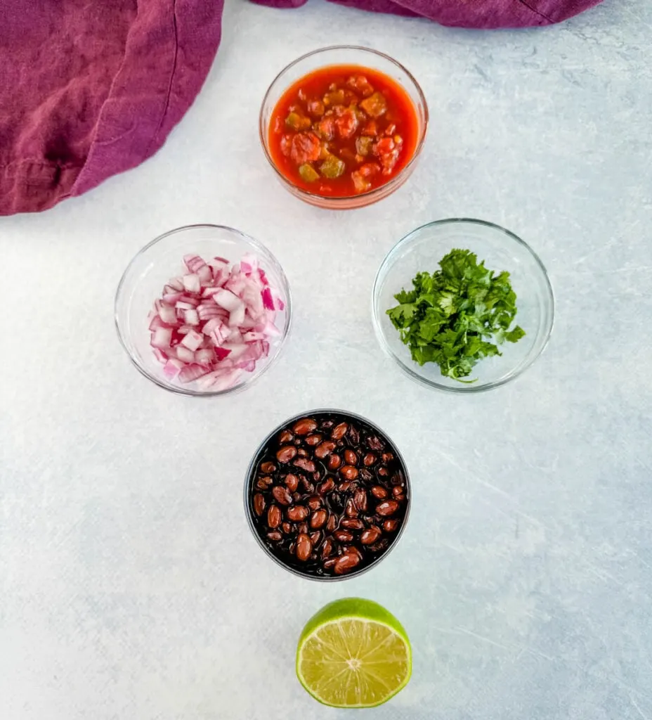 salsa, diced onions, fresh cilantro, canned black beans, and fresh lime in separate glass bowls