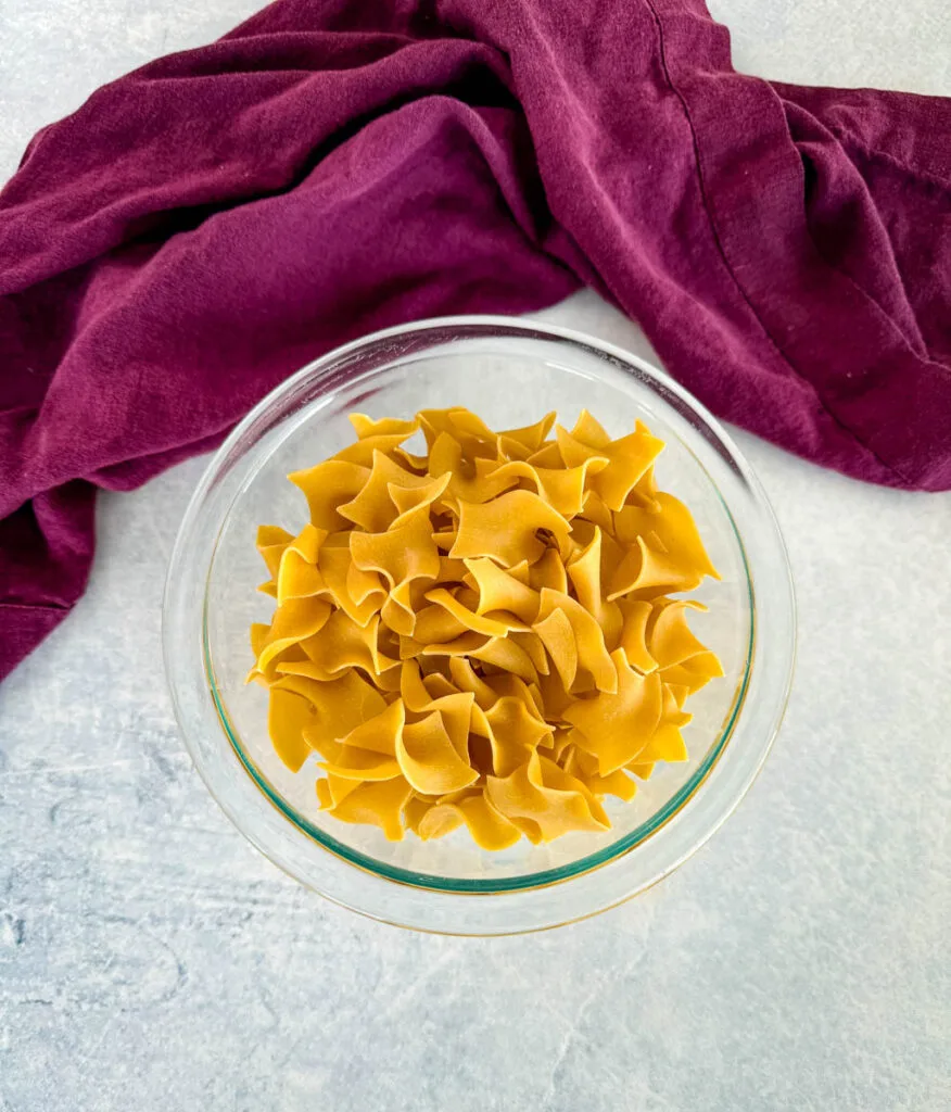 dry wide egg noodles in a glass bowl