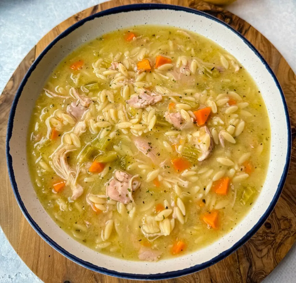 chicken orzo soup with carrots, celery in a white bowl