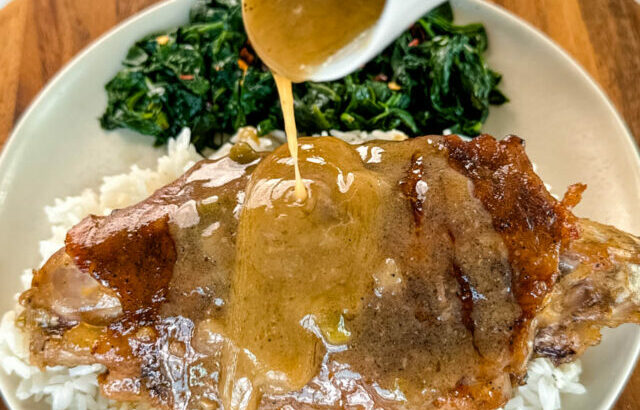 turkey wing on a plate with spinach drizzled with gravy