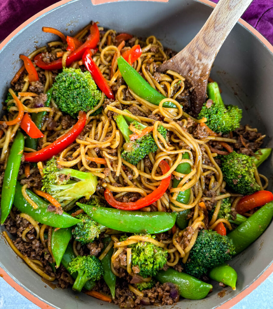 ground beef lo mein in a skillet with a wooden spoon