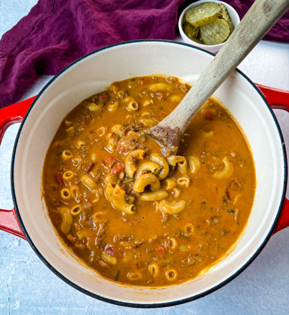 bacon cheeseburger soup with a wooden spoon in a Dutch oven