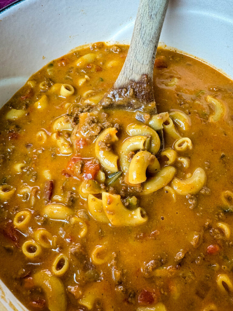 bacon cheeseburger soup with a wooden spoon in a Dutch oven