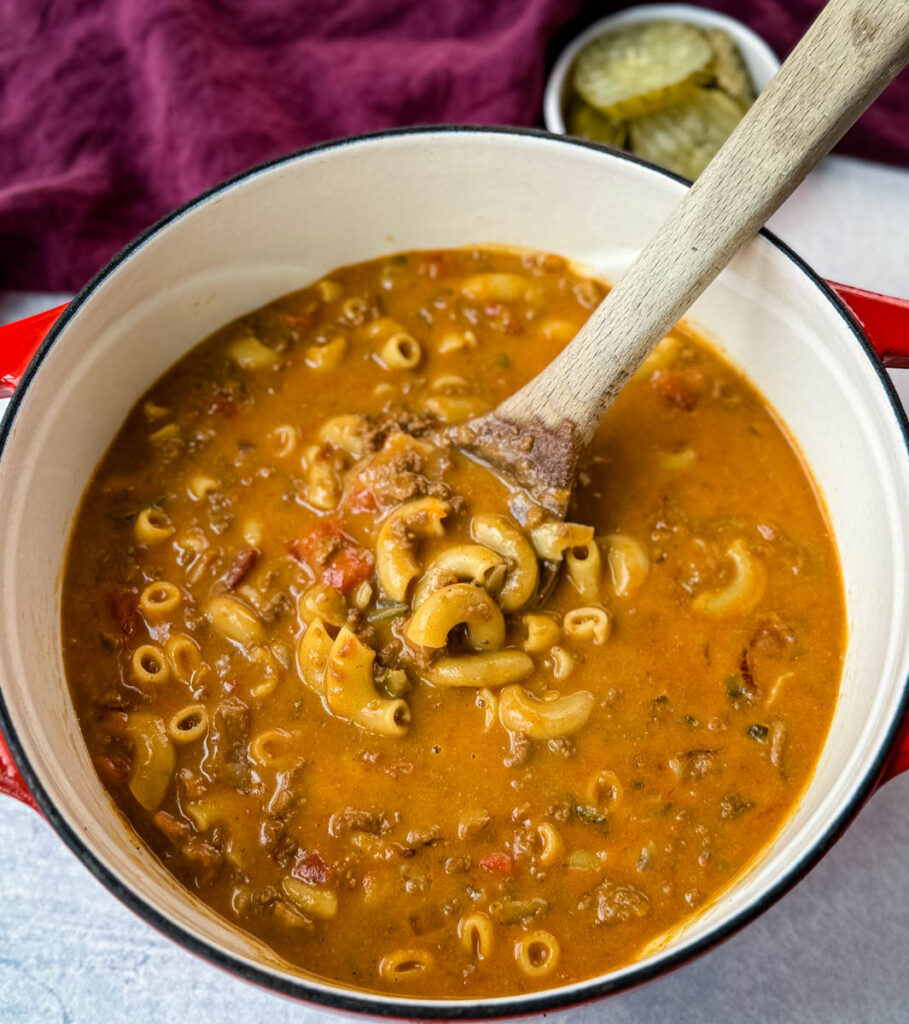 bacon cheeseburger soup with a wooden spoon in a Dutch oven