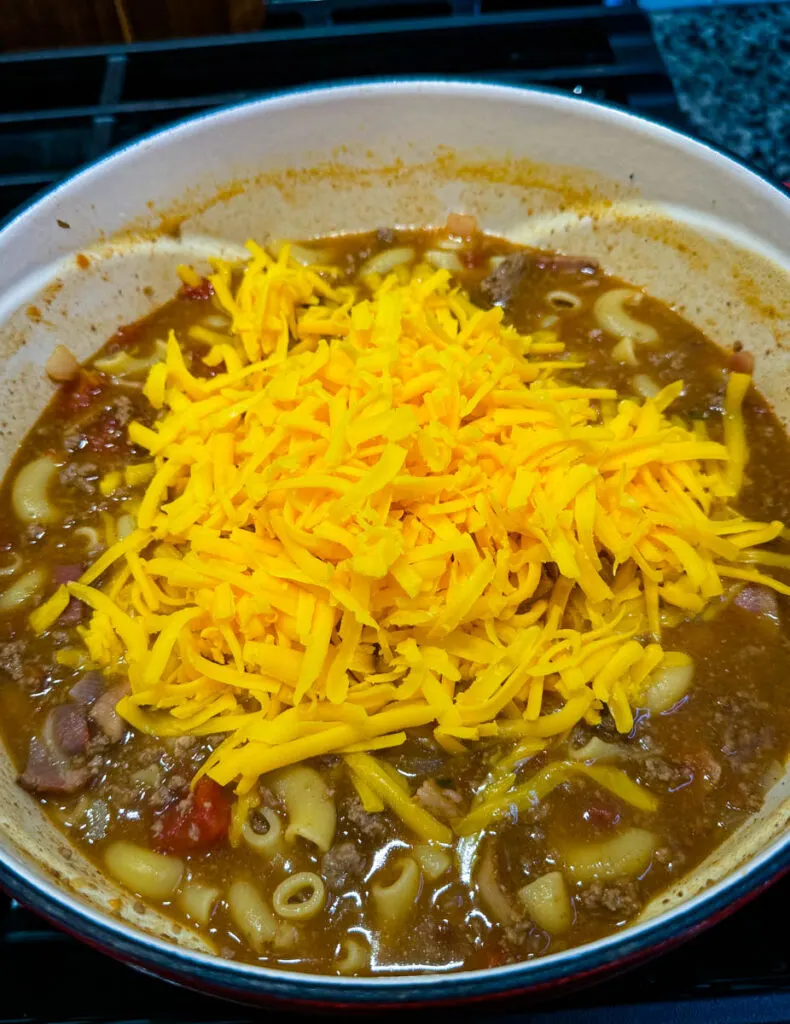 bacon cheeseburger soup with fresh grated cheese in a Dutch oven