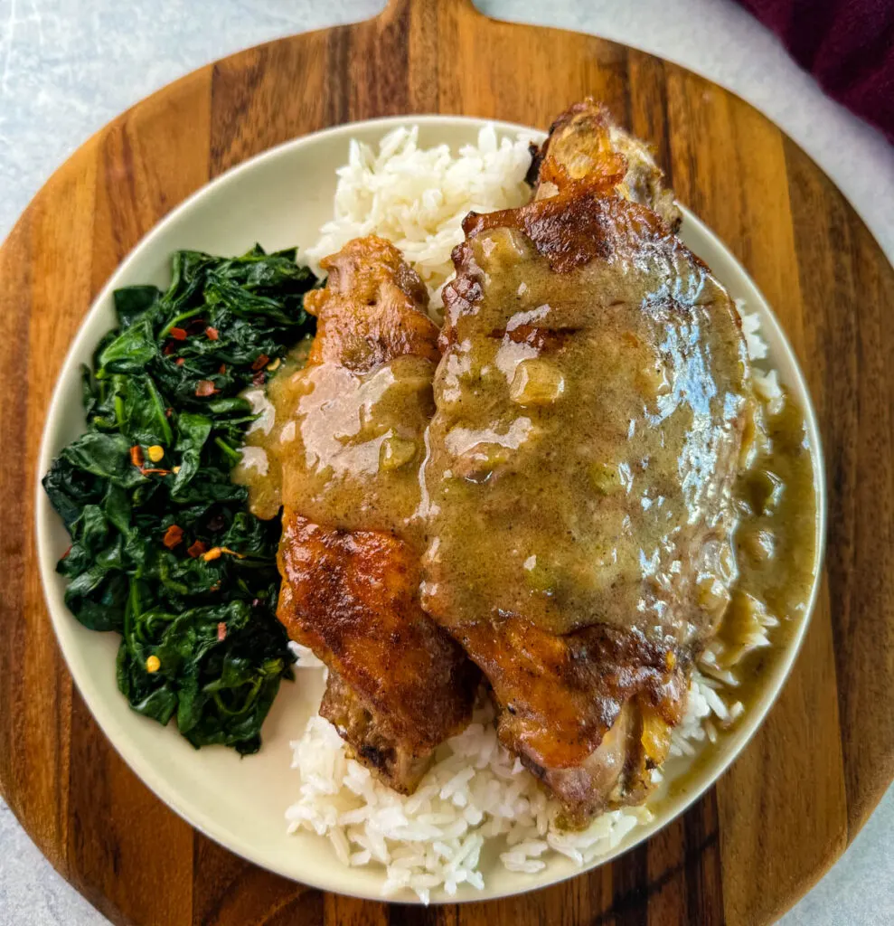 smothered turkey wings and rice on a plate with cooked spinach