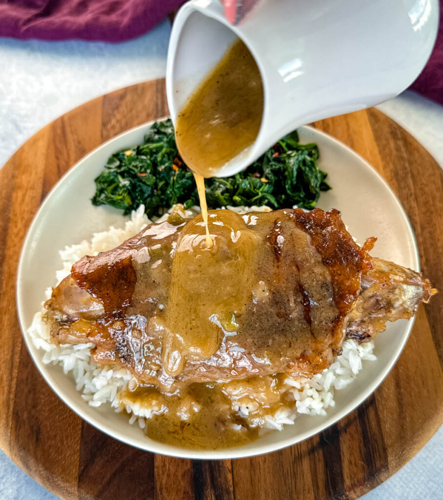 turkey wing on a plate with spinach drizzled with gravy