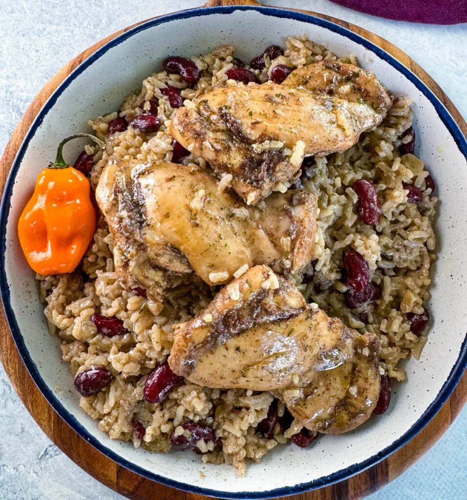 jerk chicken, rice, peas, red beans, and peppers in a white bowl