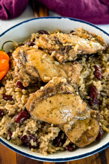 jerk chicken, rice, peas, red beans, and peppers in a white bowl