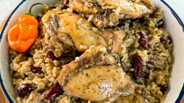 jerk chicken, rice, peas, red beans, and peppers in a white bowl