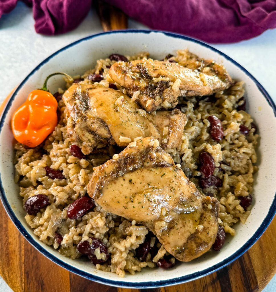 jerk chicken, rice, peas, red beans, and peppers in a white bowl