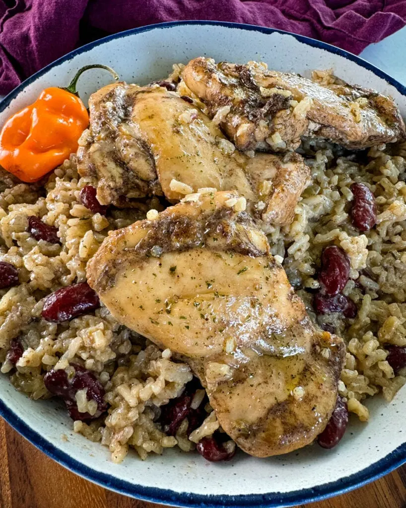 jerk chicken, rice, peas, red beans, and peppers in a white bowl