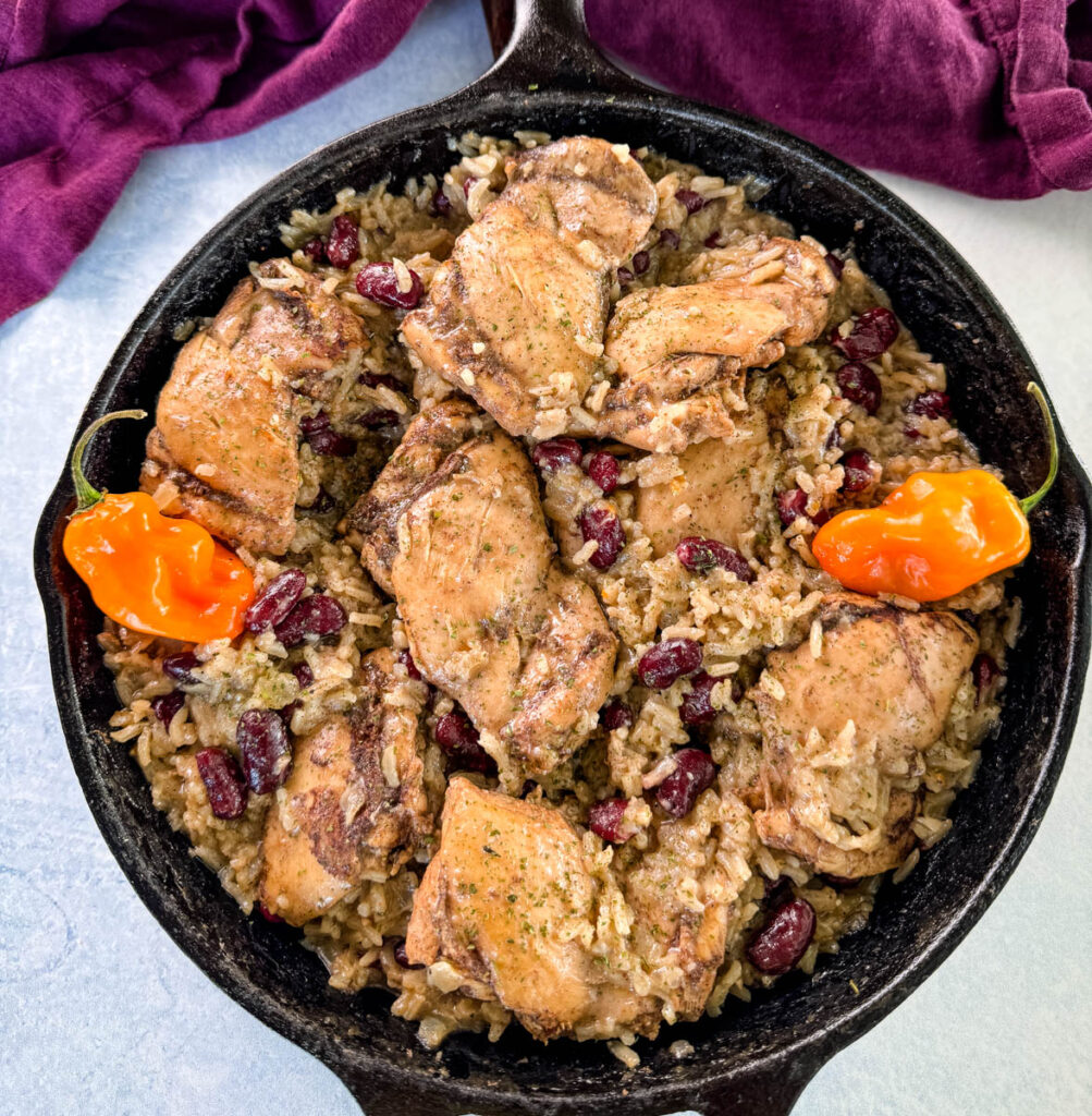 jerk chicken, rice, peas, red beans, and peppers in a cast iron skillet