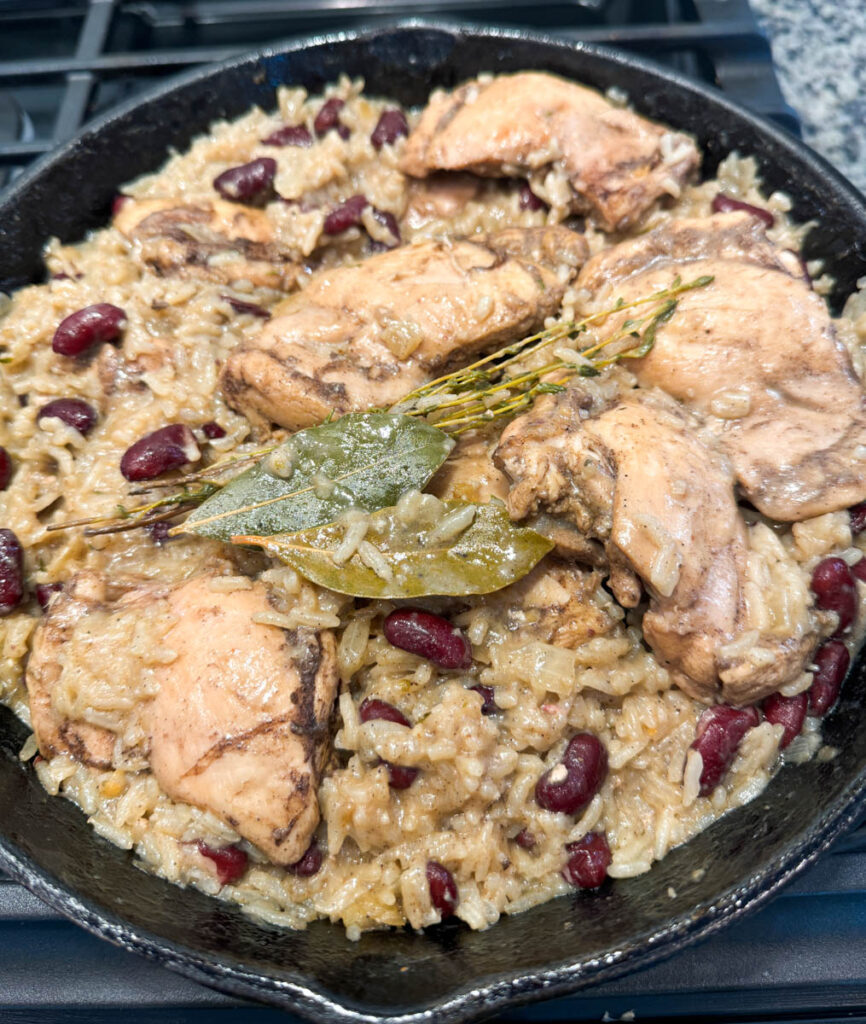 jerk chicken, rice, peas, red beans, and peppers in a cast iron skillet