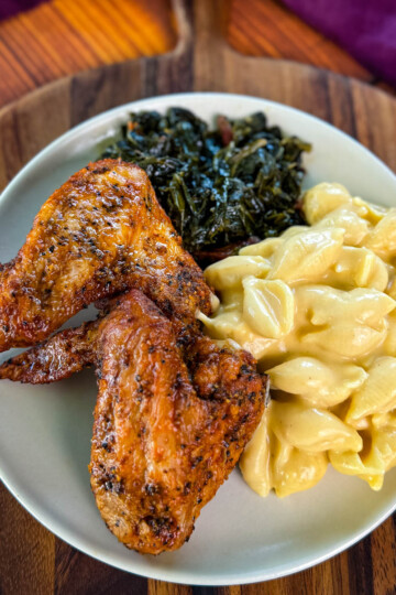 fried chicken wings, collard greens, and stovetop mac and cheese on a plate