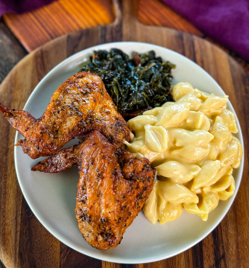 fried chicken wings, collard greens, and stovetop mac and cheese on a plate