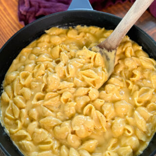 stovetop mac and cheese in a cast iron skillet with a wooden spoon