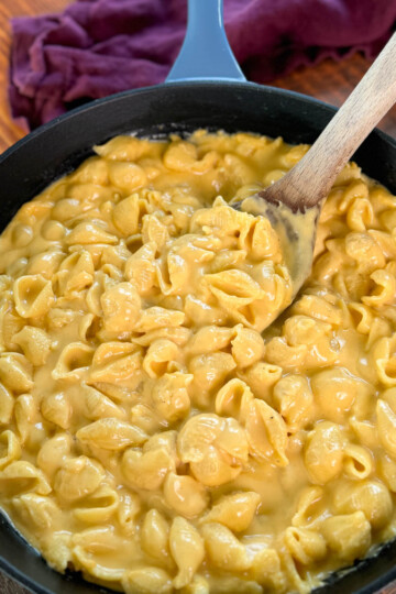 stovetop mac and cheese in a cast iron skillet with a wooden spoon