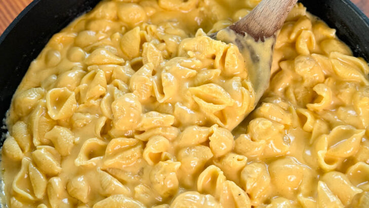 stovetop mac and cheese in a cast iron skillet with a wooden spoon