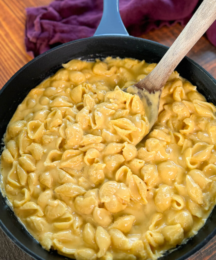 stovetop mac and cheese in a cast iron skillet with a wooden spoon