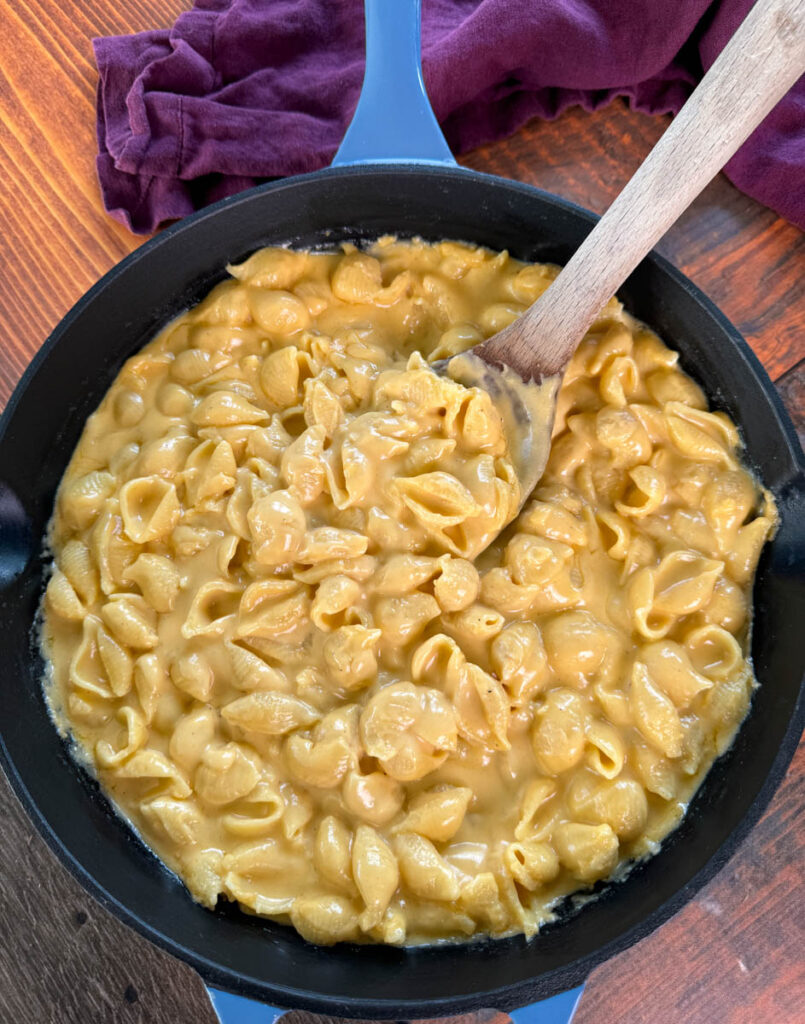 stovetop mac and cheese in a cast iron skillet with a wooden spoon