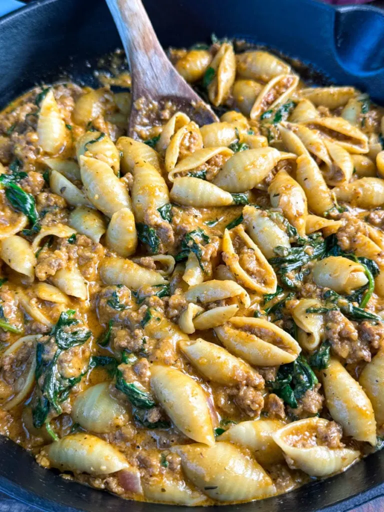 high protein beef and shells pasta with spinach in a cast iron skillet