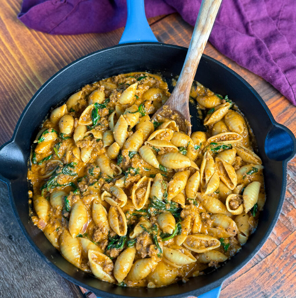 high protein beef and shells pasta with spinach in a cast iron skillet