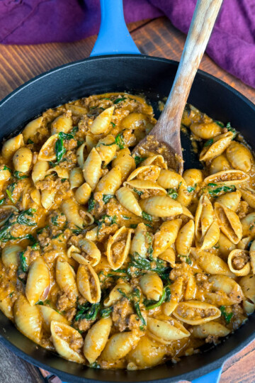 high protein beef and shells pasta with spinach in a cast iron skillet