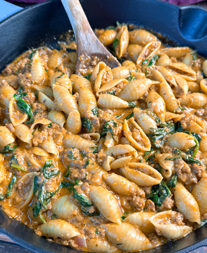 high protein beef and shells pasta with spinach in a cast iron skillet