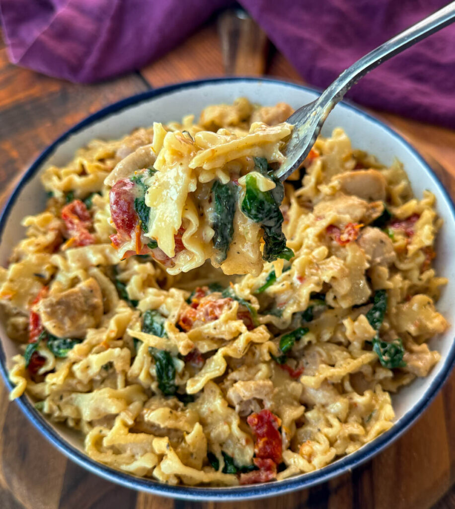 fork full of marry me chicken pasta with sundried tomatoes, parmesan, and spinach