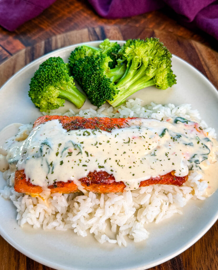 Tuscan style marry me salmon with cream sauce with rice and broccoli on a plate