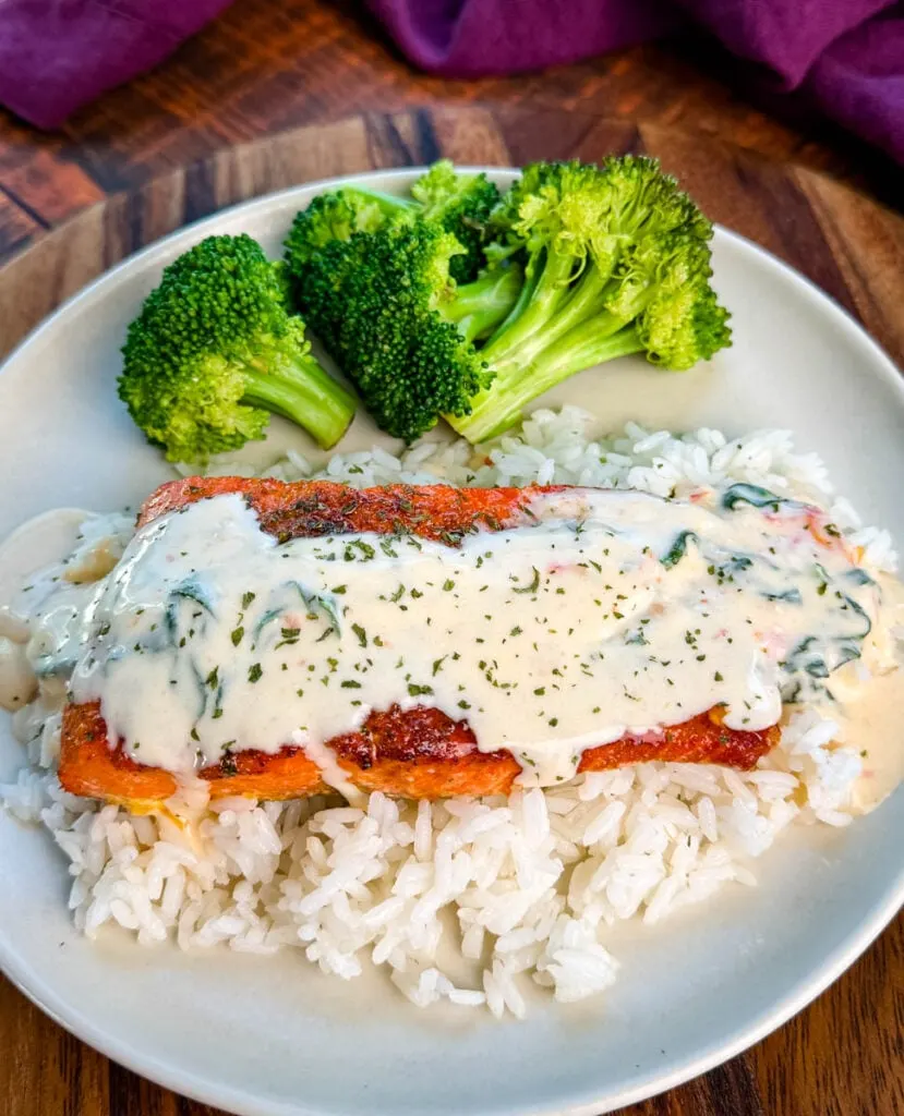 Tuscan style marry me salmon with cream sauce with rice and broccoli on a plate