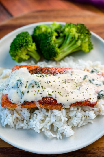 Tuscan style marry me salmon with cream sauce with rice and broccoli on a plate