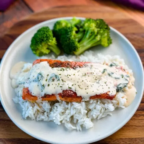 Tuscan style marry me salmon with cream sauce with rice and broccoli on a plate