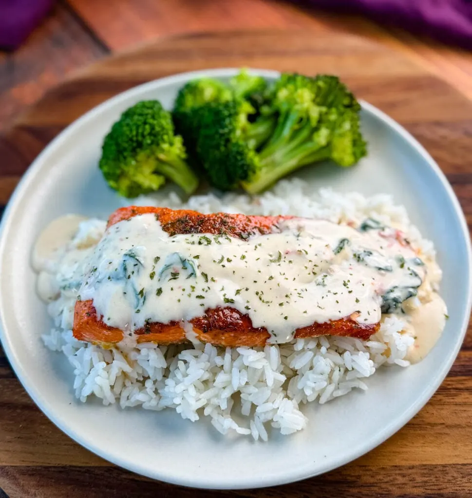 Tuscan style marry me salmon with cream sauce with rice and broccoli on a plate