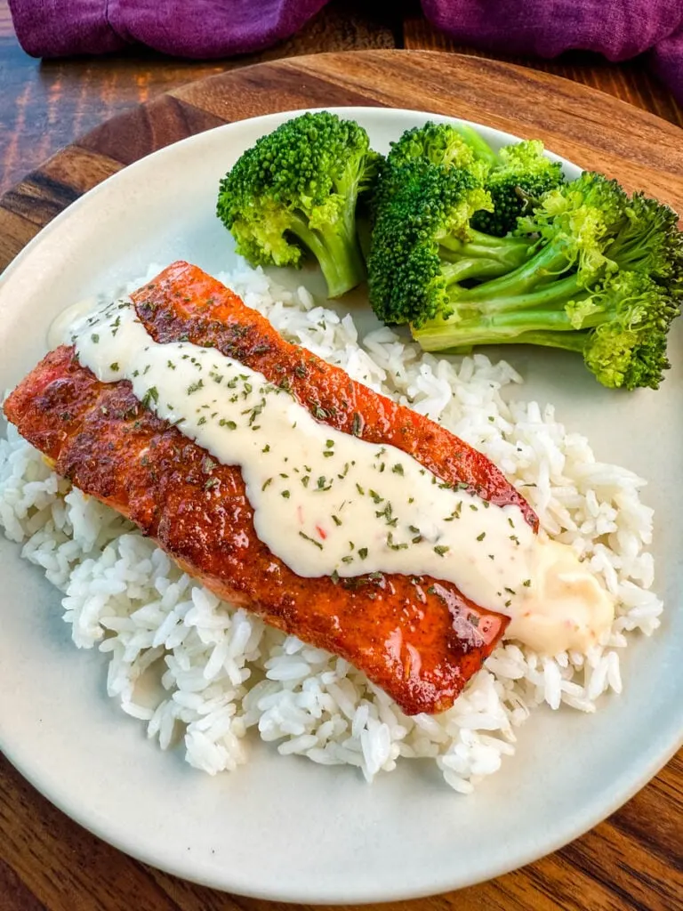 Tuscan style marry me salmon with cream sauce with rice and broccoli on a plate