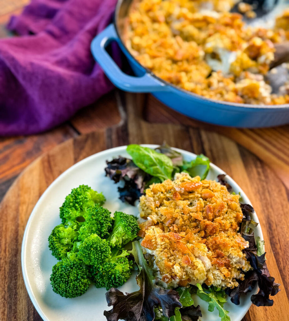 million dollar chicken casserole on a plate with mixed greens and broccoli