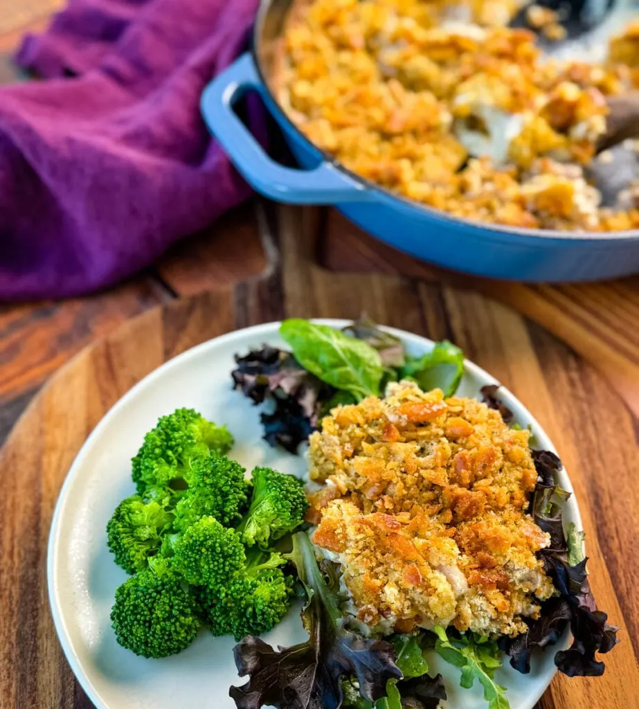 million dollar chicken casserole on a plate with mixed greens and broccoli