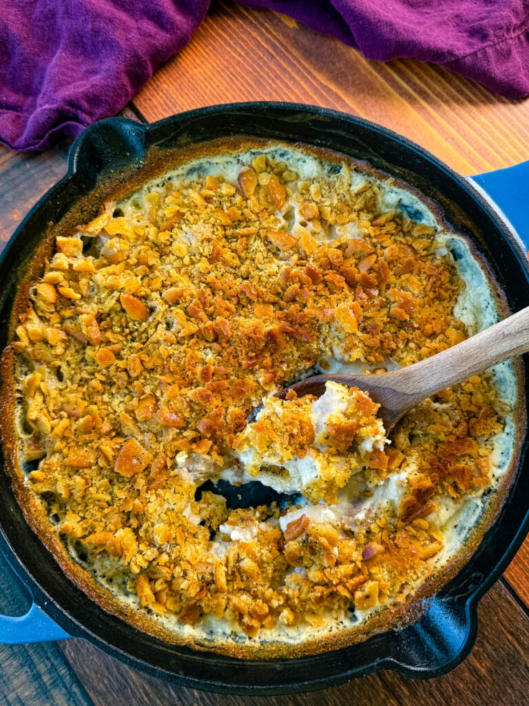 million dollar chicken casserole in a cast iron skillet with a wooden spoon