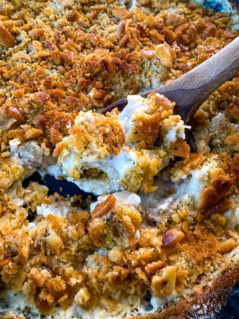 million dollar chicken casserole in a cast iron skillet with a wooden spoon