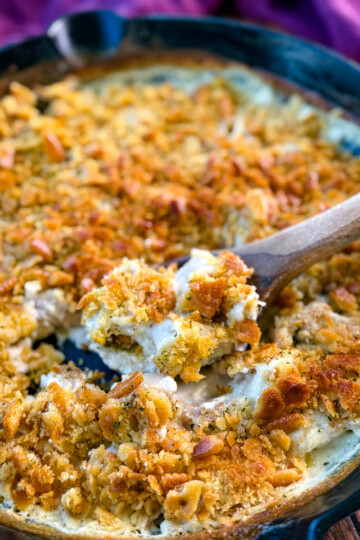 million dollar chicken casserole in a cast iron skillet with a wooden spoon