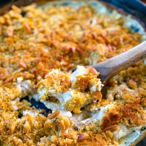 million dollar chicken casserole in a cast iron skillet with a wooden spoon